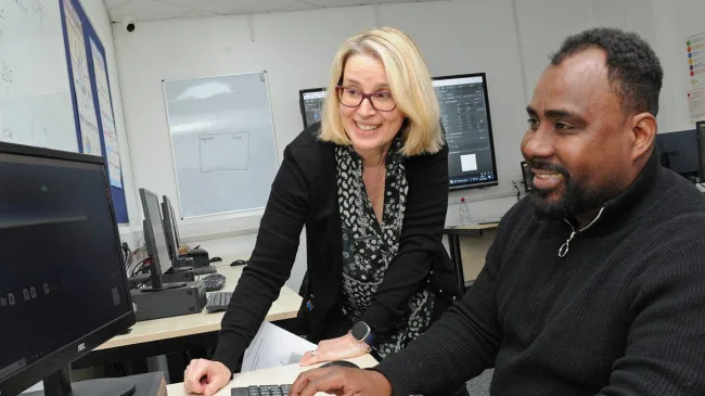 IT Adult Student With Teacher Looking At Computer